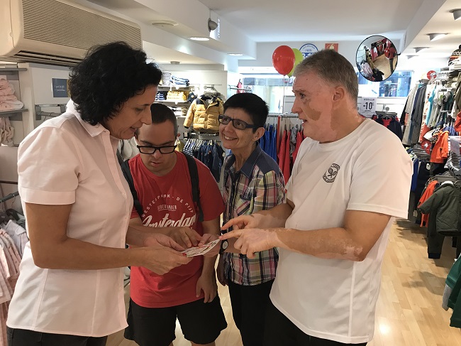 Usuaris de l'entitat explicant la campanya a un comerç del centre prodis fulletons comerços el retorn de la furgo