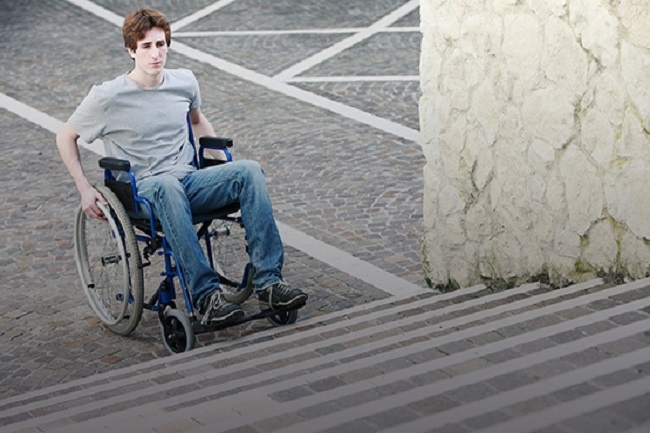 un jove amb cadira de rodes davant d'unes escales
